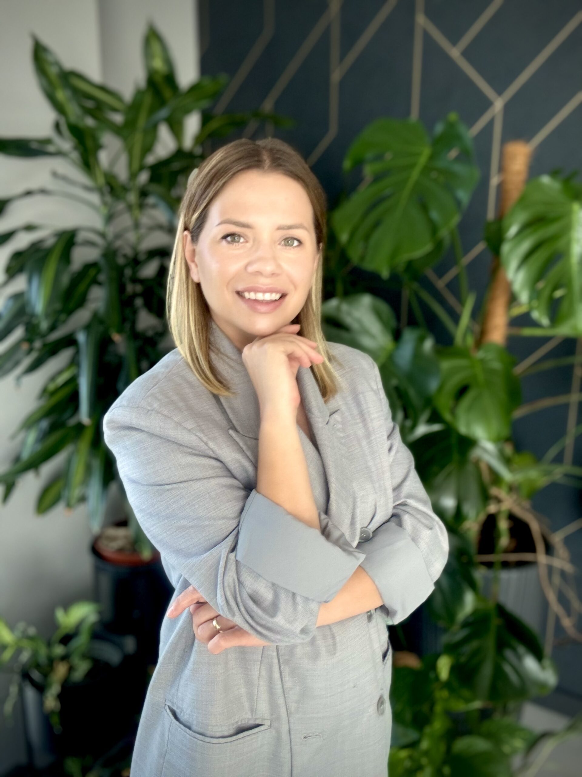 Justyna Ciesielska, certyfikowana trenerka biznesu na tle zielonych roślin